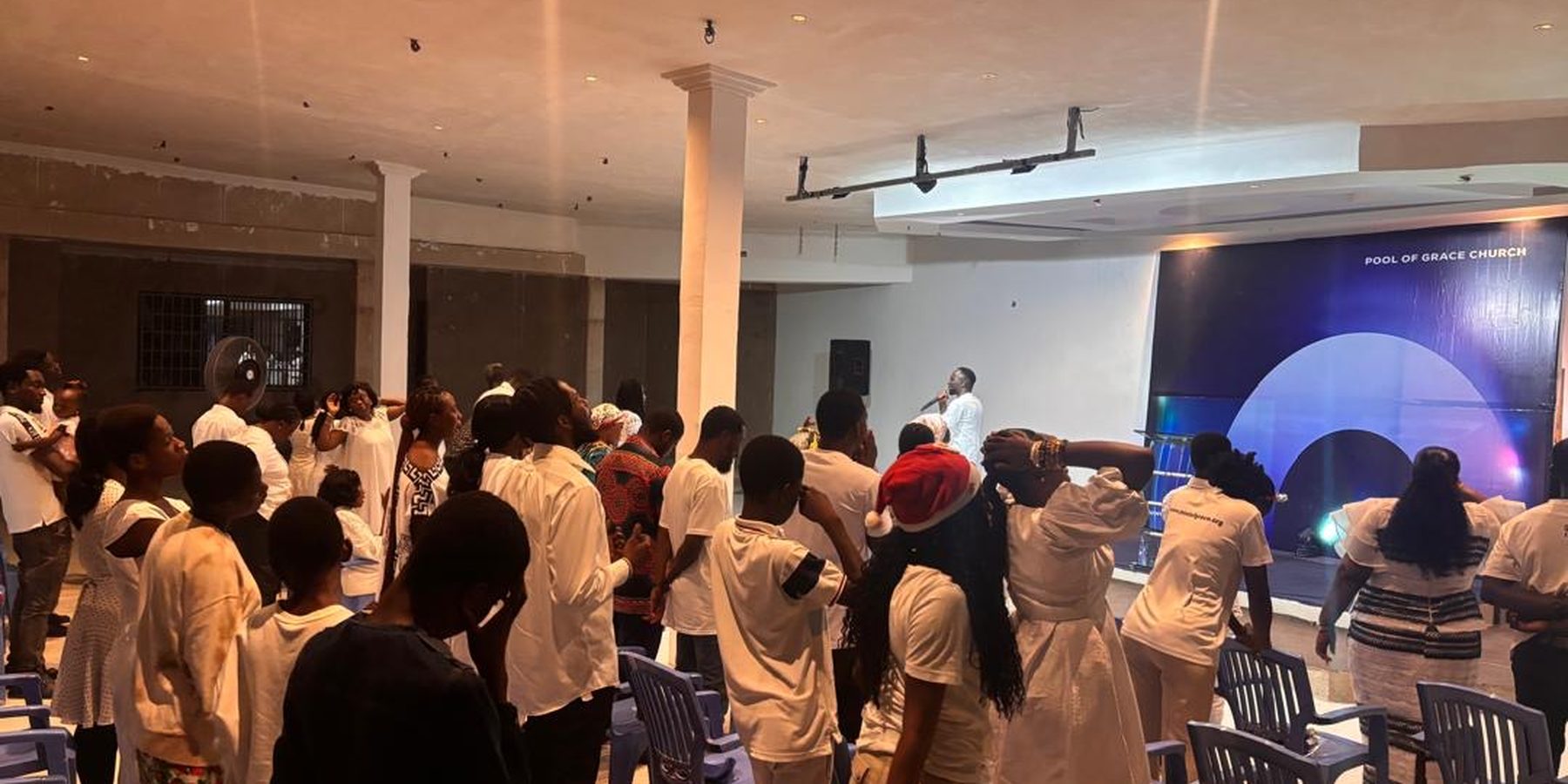 The congregation of Pool of Grace Church standing together in worship on a Sunday morning