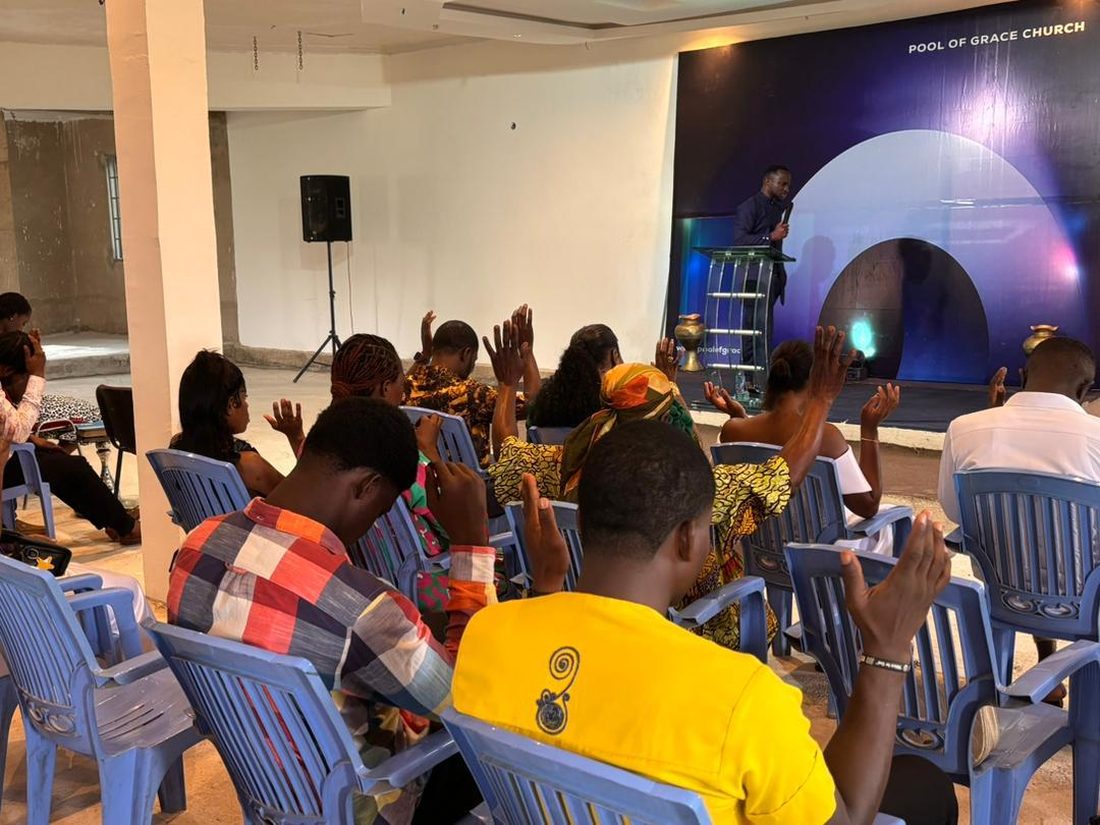 Members of Pool of Grace Church with hands raised in worship